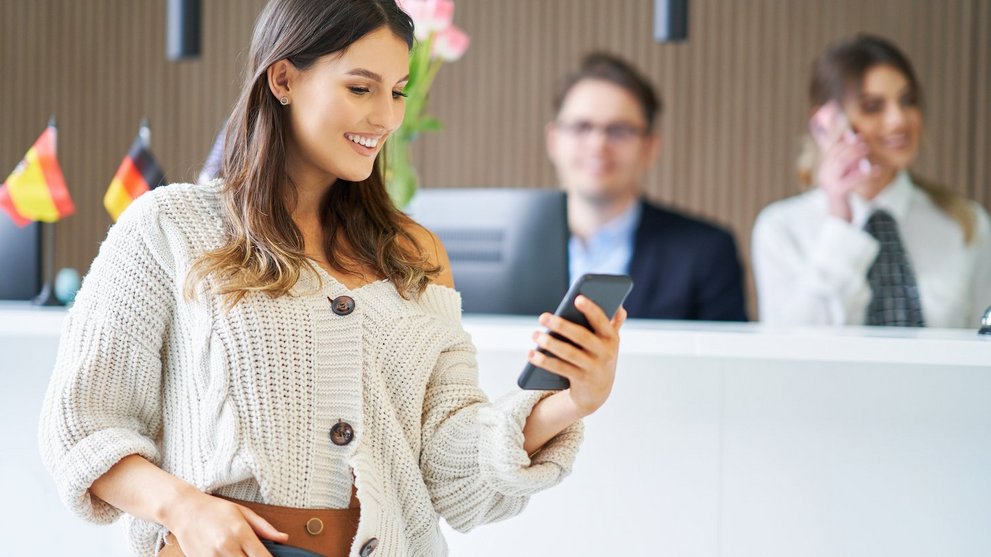 Frau mit Smartphone an einer Rezeption