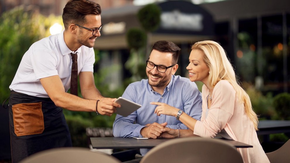 Kellner mit Digital Tablet Computer berät Gäste